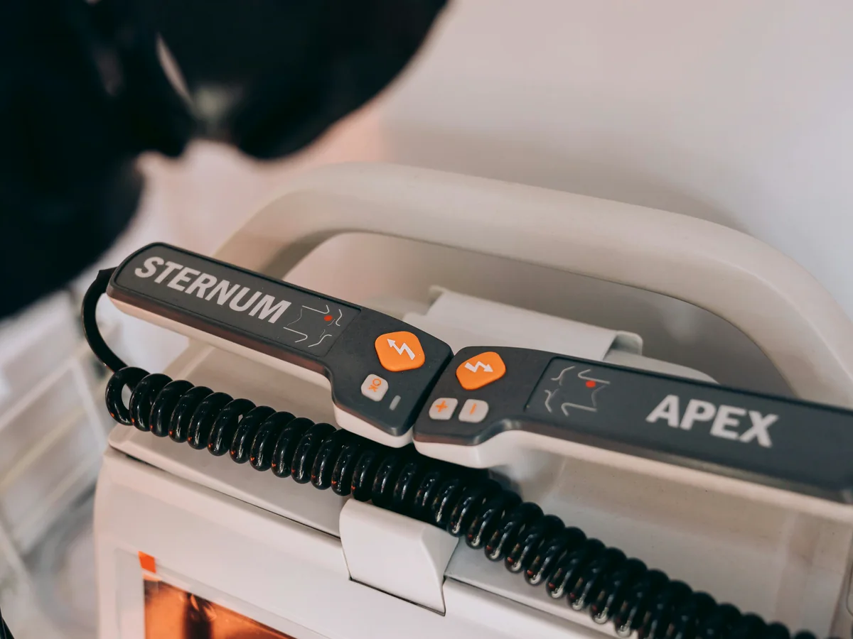 Close-up of an automated external defibrillator with pads and controls visible.